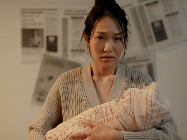 Mother resting at home with her newborn in soft natural light during early postpartum c-section recovery