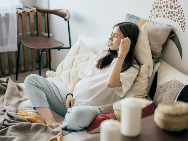 Woman in early pregnancy sitting calmly at home with soft natural light in the background
