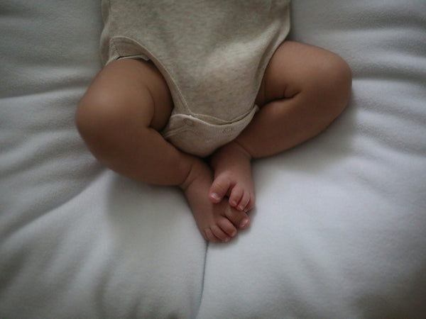 Newborn baby sleeping safely on their back in a bassinet with a firm flat surface and fitted sheet