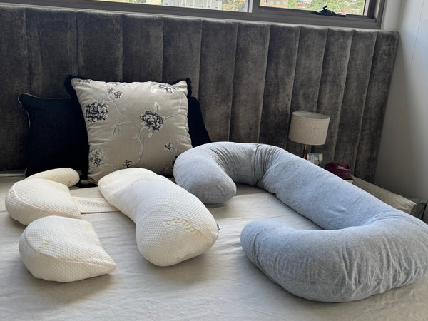 Different types of pregnancy pillows including a wedge pillow and U-shaped pillow laid out for comparison