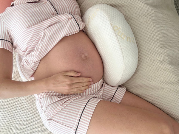 Pregnant woman lying on her side in bed during the third trimester struggling to sleep at night
