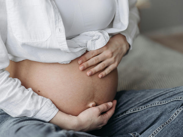 Pregnant woman in her third trimester resting at home in soft natural light with a large visible bump