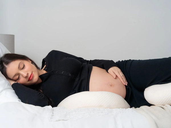 Pregnant woman sleeping comfortably on her side in a softly lit bedroom