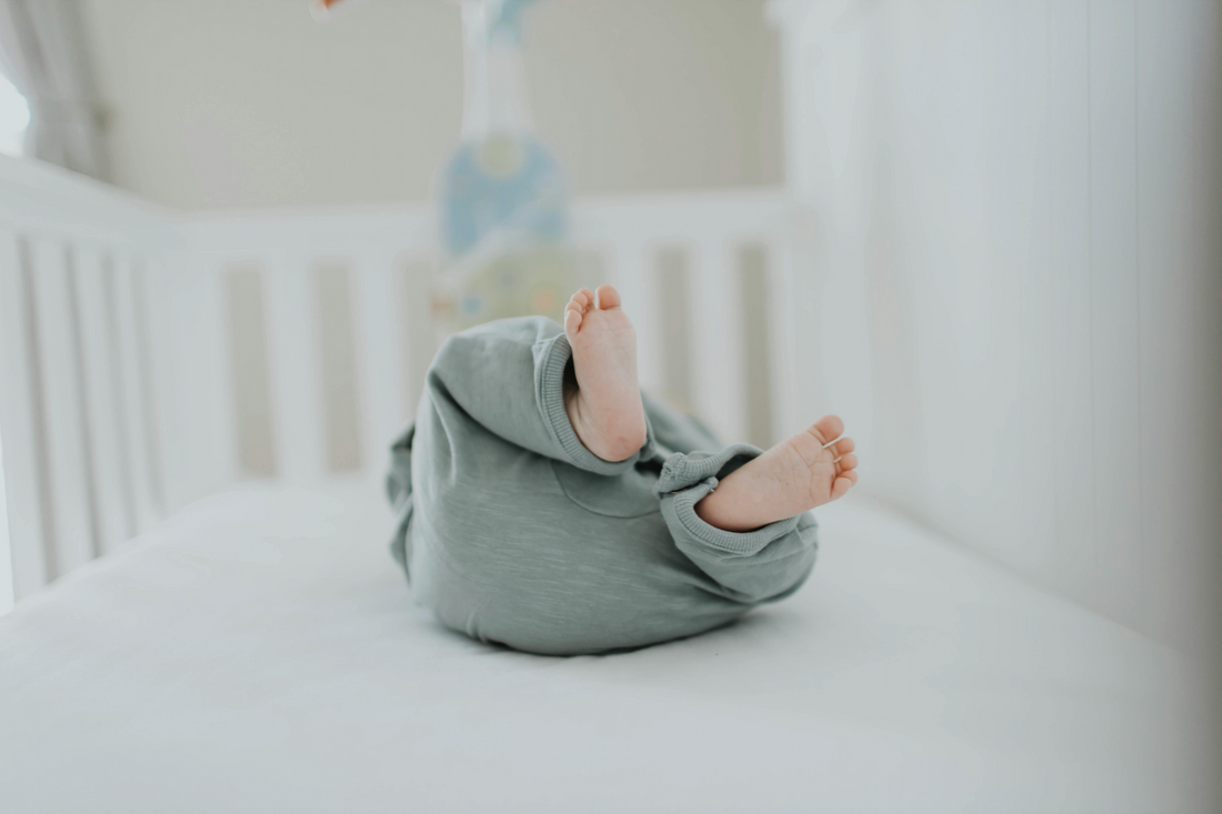 Newborn baby sleeping safely on their back in a clean bassinet with a firm flat mattress and fitted sheet