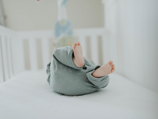 Newborn baby sleeping safely on their back in a clean bassinet with a firm flat mattress and fitted sheet
