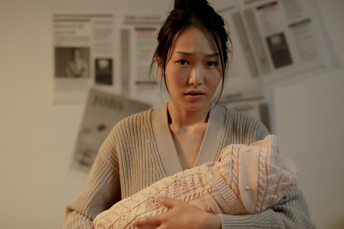 Mother resting at home with her newborn in soft natural light during early postpartum c-section recovery