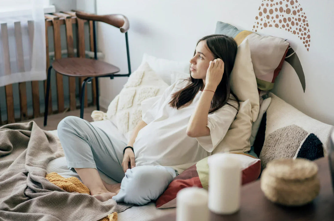 Woman in early pregnancy sitting calmly at home with soft natural light in the background
