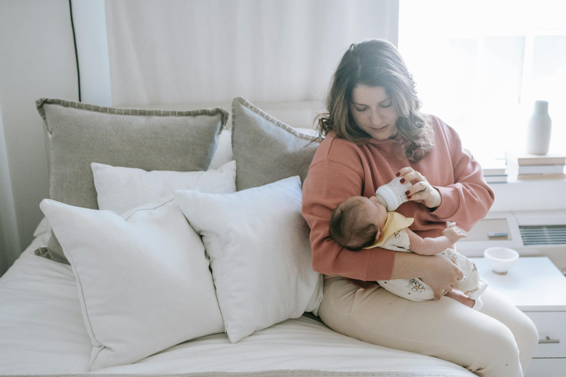 Mother holding her newborn baby in a quiet dimly lit room during the early postpartum fourth trimester