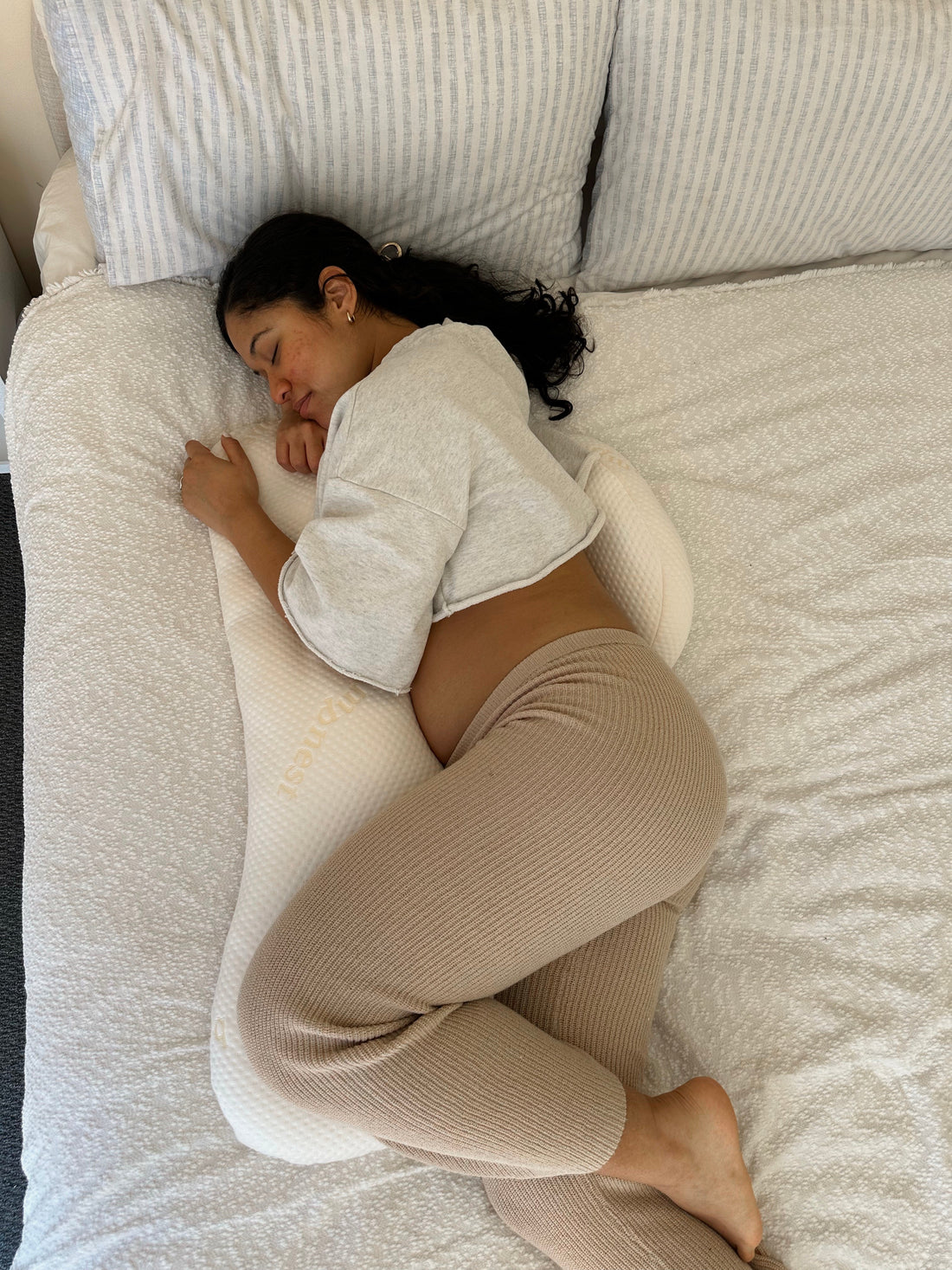 Pregnant woman lying on her side in bed at night with hip and pelvic pain during pregnancy