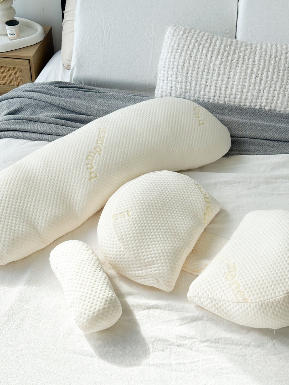 Maternity pillow and body pillow side by side on a bed showing the difference in shape and support
