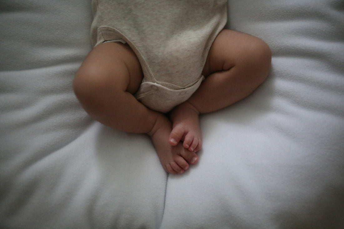 Newborn baby sleeping safely on their back in a bassinet with a firm flat surface and fitted sheet