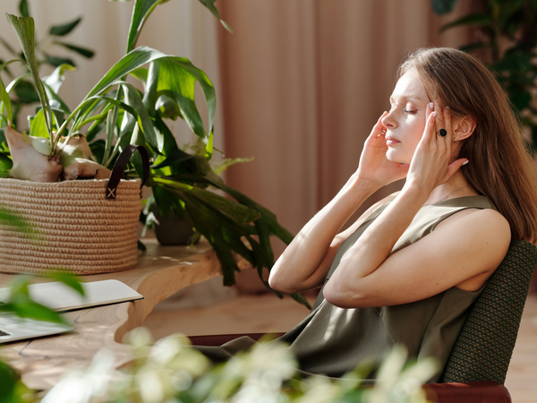 Pregnant woman sitting calmly at home with hand resting at her temple experiencing a pregnancy headache