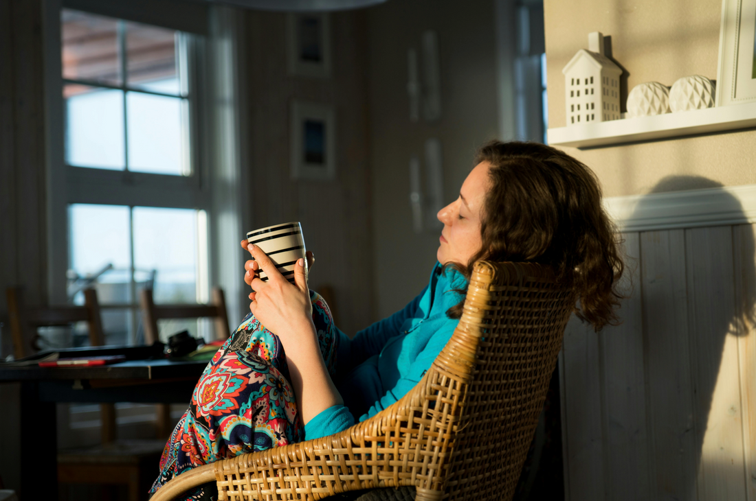 Woman sitting quietly at home in soft morning light managing pregnancy nausea in the first trimester