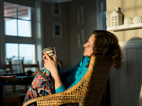 Woman sitting quietly at home in soft morning light managing pregnancy nausea in the first trimester