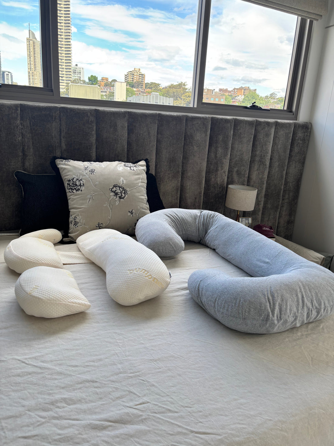 Different types of pregnancy pillows including a wedge pillow and U-shaped pillow laid out for comparison