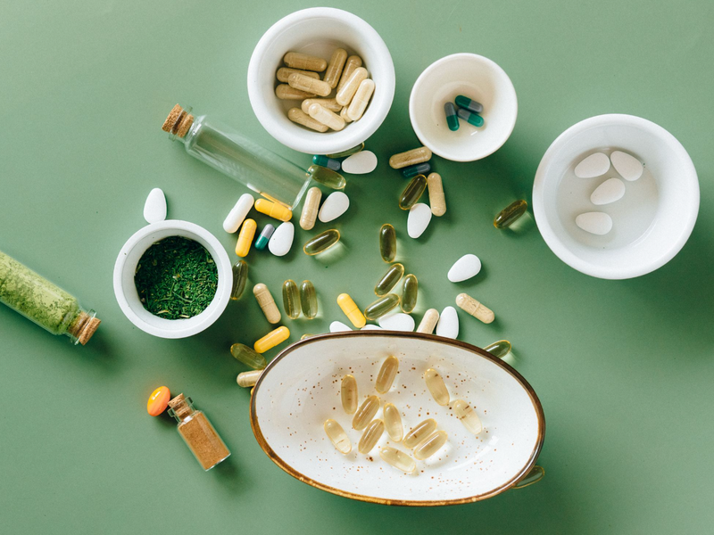 Pregnancy supplements and fresh whole foods arranged on a neutral surface in natural light
