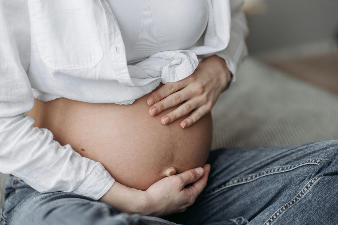 Pregnant woman with hands resting gently on her bump representing the pregnancy week by week journey