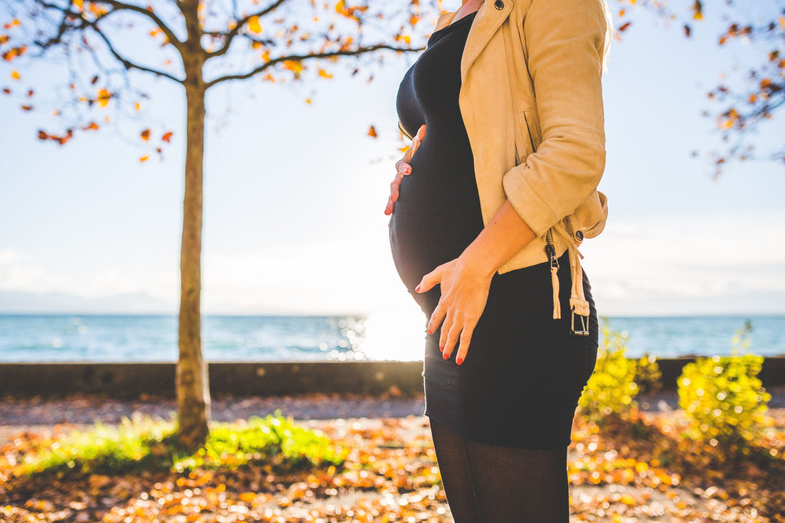 Pregnant woman standing outdoors in soft morning sunlight during pregnancy