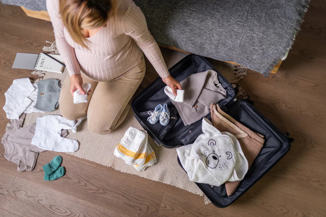 Neatly packed hospital bag with baby clothes and pregnancy essentials laid out on a bed