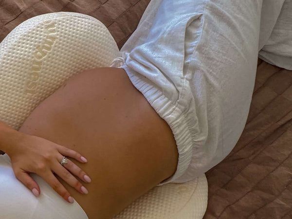 Pregnant woman sleeping comfortably on her side with pregnancy pillow support in soft natural light