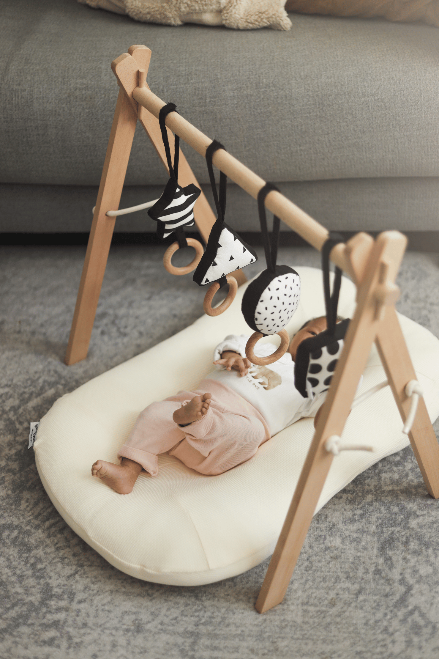 Newborn baby in baby lounger under play gym in Bumpnest Baby Pod during supervised tummy time and play