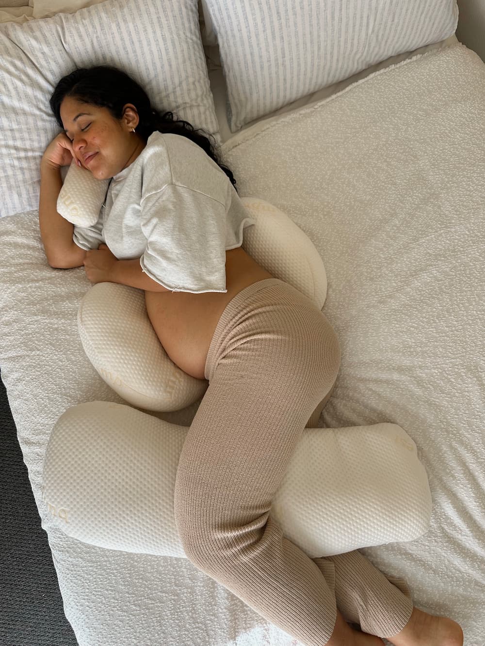 Pregnant woman smiling in bed supported by Bumpnest adjustable pregnancy pillow Australia